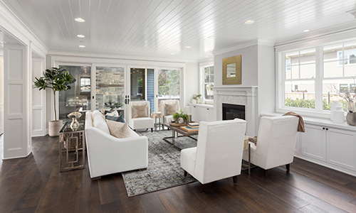 Beautiful living room in new luxury home with white ceiling, hardwood floors, white cabinets and white furniture.